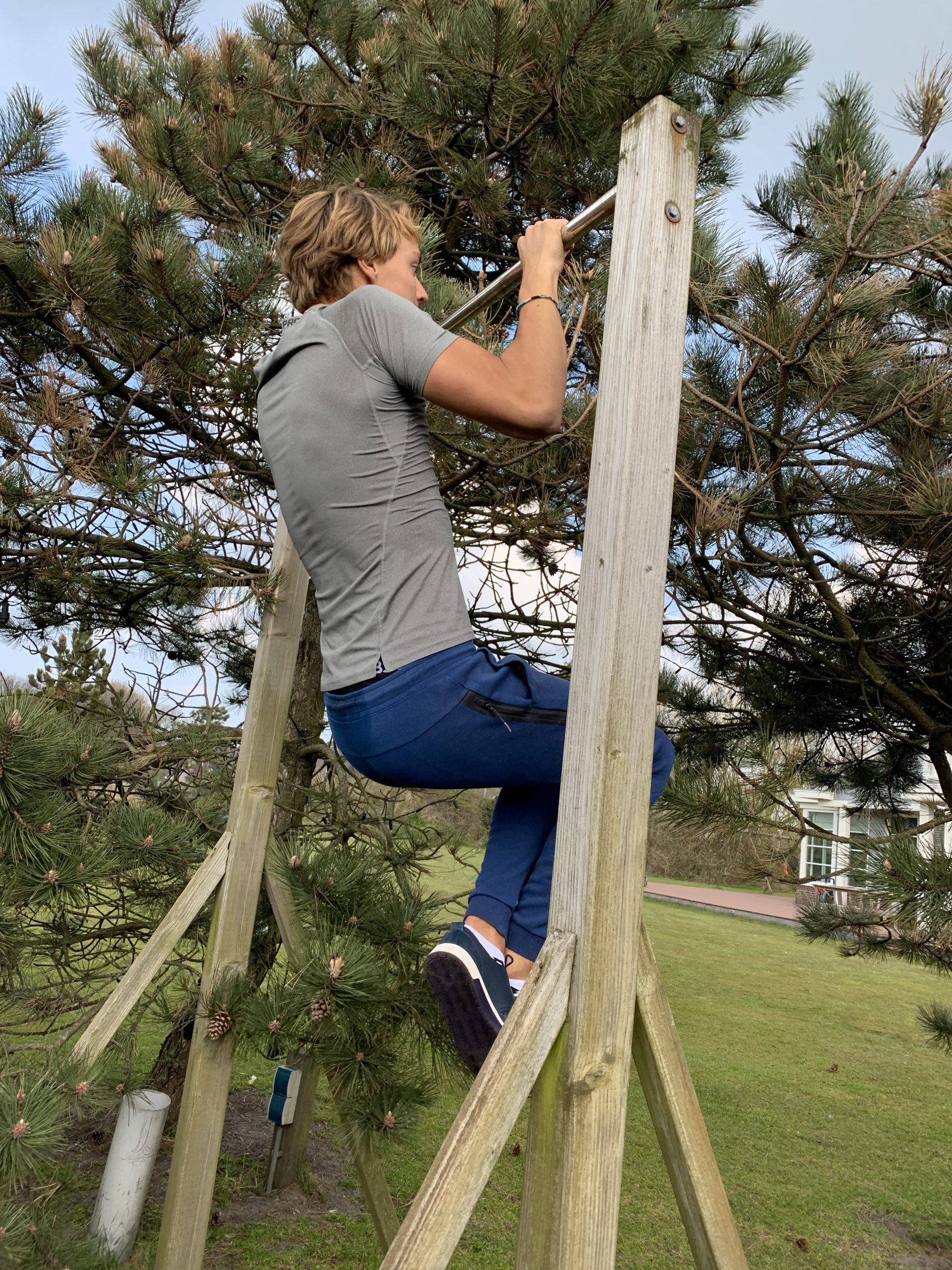 Een jongen trekt zich op aan een optrekstang tijdens personal training om fysiek sterk en mentaal weerbaar te worden